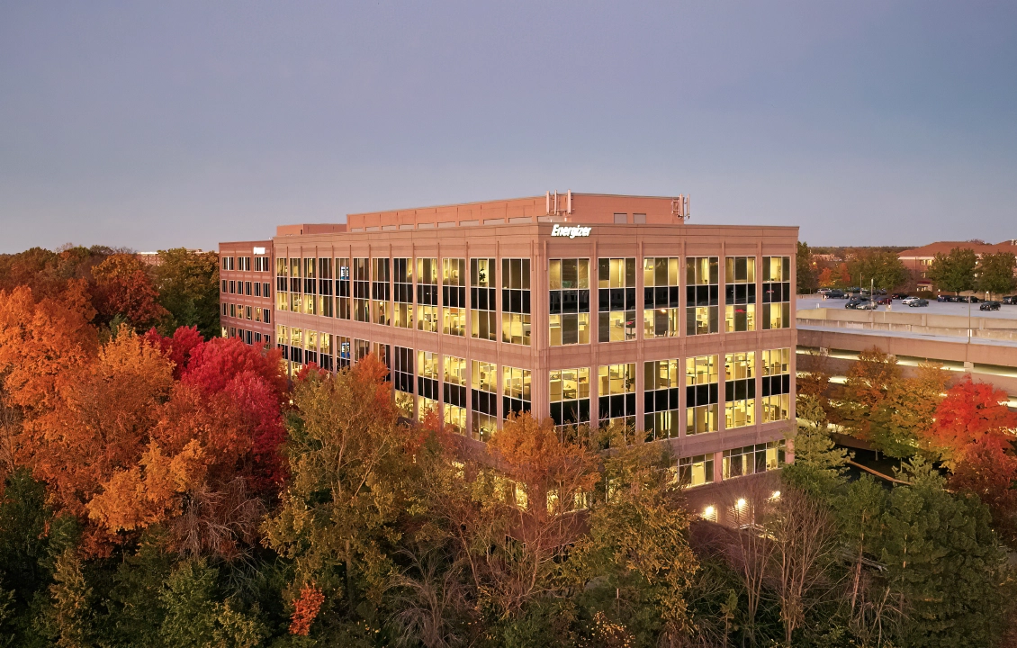 Modern office building surrounded by colorful autumn trees at dusk.