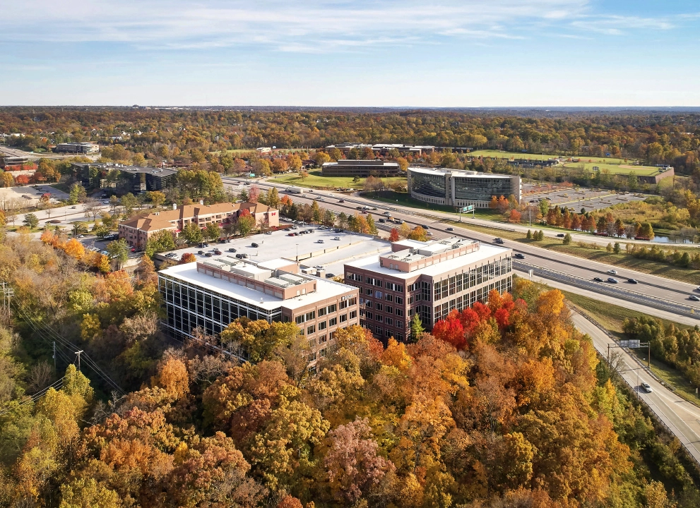 Aerial view of office buildings surrounded by colorful fall foliage.